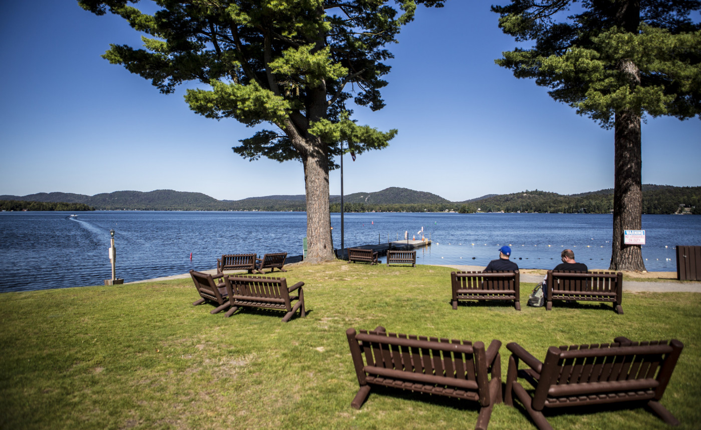 A park with benches close to a lake on a sunny day.