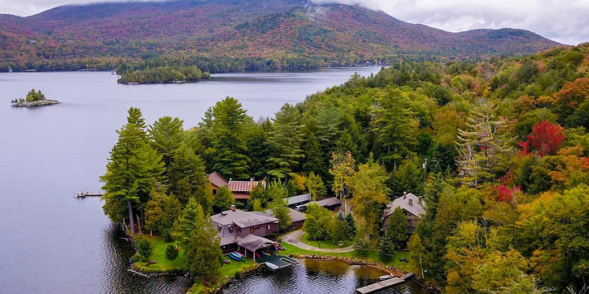 An Adirondack lodge and cabins on a lake, as viewed from the air.