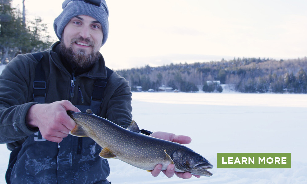 A man smiling, holding up a Northern Pike on a frozen lake and a Learn More button.